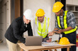 © ArLawKa - Three colleagues discussing data work and tablet Laptop with architecture project at construction site Architect team working on blueprints for architectural plans construction project engineer