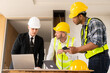 © ArLawKa - Three colleagues discussing data work and tablet Laptop with architecture project at construction site Architect team working on blueprints for architectural plans construction project engineer