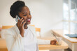 © Strelciuc - Portrait of young african american woman talking on mobile phone at cafe looking away while drinking an ice coffee. Modern female lifestyle. Female using mobile