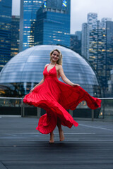 Young woman traveller in red dress looking beautiful landscape of singapore city with sunset sky , the most famous tourist attraction in singapore, Travel andvacation in singapore. 