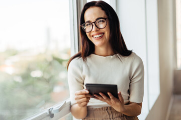 Poster - Happy female professional holding a tablet in an office