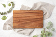 Wood cutting board on linen napkin with leaves on marble background