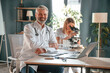 © standret - Man is smiling, woman is using microscope. Two clinic workers are indoors together