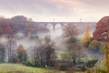 Morning Mist Swirling Among The Autumn Coloured Trees And Railway Viaduct At Dane-In-Shaw Pasture, Cheshire, England