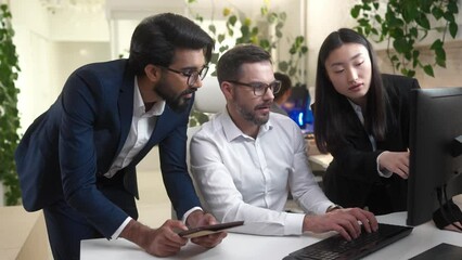 Portrait of multiethnic group of colleagues working in IT company discussing doing tasks and projects. Young handsome Indian manager, professional caucasian male programmer and female asian employee.