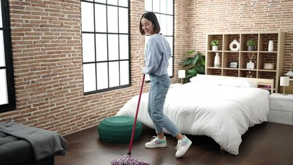 Wall Mural - Young beautiful hispanic woman cleaning floor using mop as a guitar at home