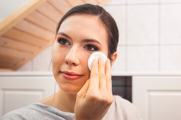 Wall Mural - Waist up close up portrait of a young woman removing make up in her bathroom at night 