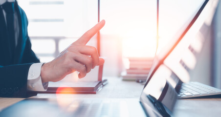 businessman working in office pointing to blurred computer laptop and blurred office background, office working place atmosphere