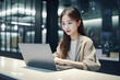 © Surachetsh - Office Working Girl, Pretty and Cute Asian Smile is sitting in front of Laptop Computer in Office Environment Background created with generative AI.