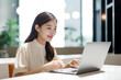 © Surachetsh - Office Working Girl, Pretty and Cute Asian Smile is sitting in front of Laptop Computer in Office Environment Background created with generative AI.