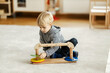 © Dusan Petkovic - A kindergartener is sitting on the floor and playing with educational toy while learning logic and motor skills.