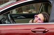 funny woman with towel on head looking from car lateral door window.always in hurry female wet hair serious face visible only eyes red vehicle.woman wearing round glass frame pink color wizard shape