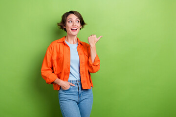 Photo of positive lovely lady wear orange trendy outfit thumb direct empty space special proposition isolated on green color background