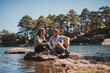 © ADDICTIVE STOCK - Cheerful friends sitting on stone in lake water