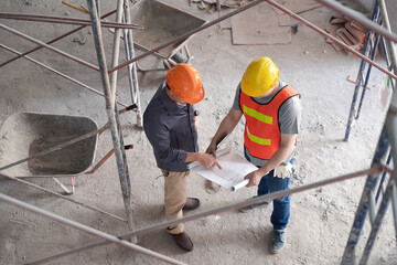 Wall Mural - Top view of Confident team of architect working together in building construction site. They discussing about new startup project. Architect discuss with engineer about project.