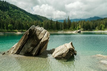 Wall Mural - Large rocks on the Caumasee lake shore under a cloudy sky in the Grisons, Switzerland