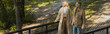 © LIGHTFIELD STUDIOS - Positive middle aged couple walking on bridge in park, banner.