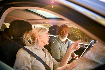 Wall Mural - Confused Senior Couple On Day Trip Out Driving In Car Reading Map Looking Lost