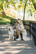 © LIGHTFIELD STUDIOS - Mature woman in sunglasses holding coffee to go near labrador on bridge in park.
