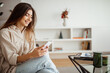 © Prostock-studio - Smiling pretty millennial mixed race woman looking at phone, reading message, chatting, surfing in internet