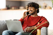 © Prostock-studio - Remote Work. Smiling Indian Freelancer Guy Using Laptop And Cellphone At Home
