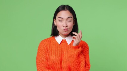 Wall Mural - Excited smart young woman of Asian ethnicity wears orange sweater look around think scratches at temple comes up with idea raised finger get plan isolated on plain pastel light green color background