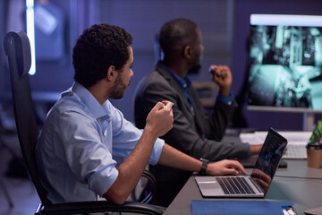 Side view portrait of two men looking at dgital board during meeting in IT security office