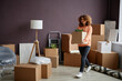 © Seventyfour - Young woman carrying cardboard boxes with things in her new apartment