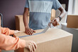 © Seventyfour - Close-up of multiethnic couple using adhesive tape for packing things in cardboard boxes