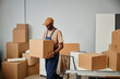 © Seventyfour - African American worker in uniform carrying cardboard boxes during relocation in new office