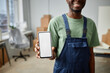 © Seventyfour - African American worker in uniform showing the screen of his smartphone while working on relocation