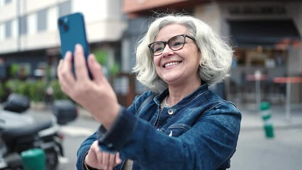 Poster - Middle age woman with grey hair smiling confident having video call at street