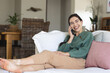 © Wavebreak Media - Happy caucasian young woman talking over mobile phone while relaxing on sofa at home