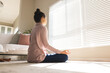 © Wavebreak Media - Low angle view of caucasian young woman meditating in front of window blinds while sitting on floor