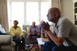© Wavebreak Media - Group of emotional, diverse senior friends in living room, talking during group therapy session