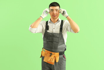 Poster - Young carpenter in safety goggles on green background