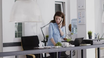 Canvas Print - Executive assistant answering landline phone call in startup office, working on business development. Professional manager using office cord telephone to have remote chat at desk.