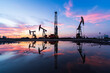 © zhengzaishanchu - in the evening, oil pumps are running, The oil pump and the beautiful sunset reflected in the water, the silhouette of the beam pumping unit in the evening.