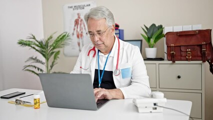 Wall Mural - Middle age man with grey hair doctor using laptop working at clinic