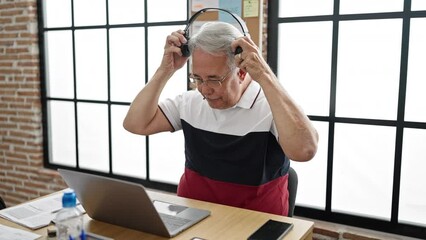 Canvas Print - Middle age man with grey hair business worker using laptop wearing headphones at office