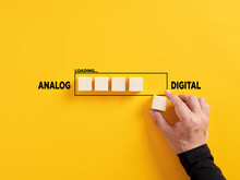 Transition of technology from analog to digital. Technological transformation. Hand places a wooden cube to the loading bar with the words analog and digital.