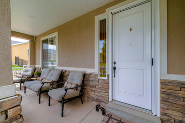 Wall Mural - Entrance to a house with relaxing cushioned chairs at the open porch. A closed white front door beside a sidelight can also be seen at the facade of this home.