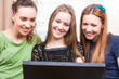 © danmorgan12 - Lifestyle Ideas. Group of Three Young Laughing Caucasian Girlfriends Having Fun With Personal Laptop Computer Indoors.