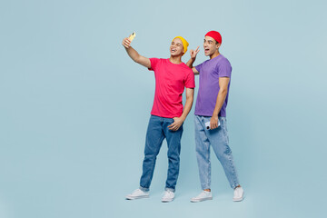 Sticker - Full body happy smiling young couple two friend men wear casual clothes together doing selfie shot on mobile cell phone show v-sign isolated on pastel plain light blue cyan background studio portrait