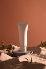 Canvas Print - An empty label white tube standing on stone podium with sand covered all around and small green trees. Cosmetic product mockup