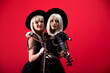 © diter - Violinist women duet in the stage costumes on the red background.