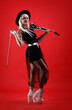 © diter - Violinist woman in the stage costume on the red background.