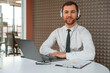 © standret - In the headphones. Handsome man in formal clothes is working by laptop in the office