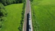 aerial view of a moving passenger train through a green landscape,