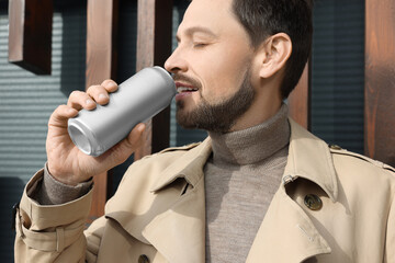 Wall Mural - Handsome man drinking from tin can outdoors, closeup